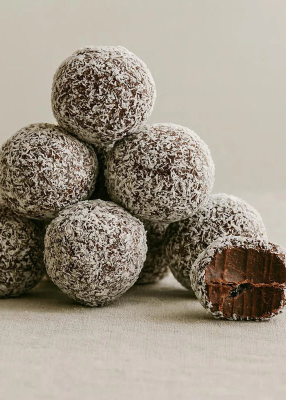 Stack of chocolate rumballs with one cut open on a neutral background