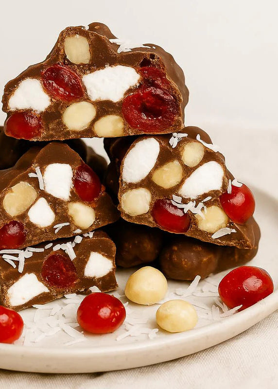 Stack of rocky road treats with nuts and berries on a white plate