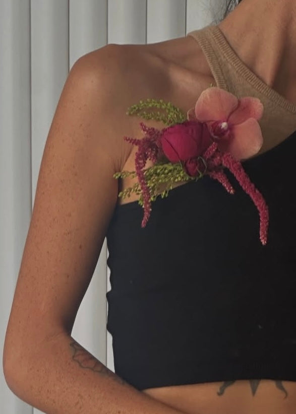 Pink and green floral boutonniere pinned onto a shirt.