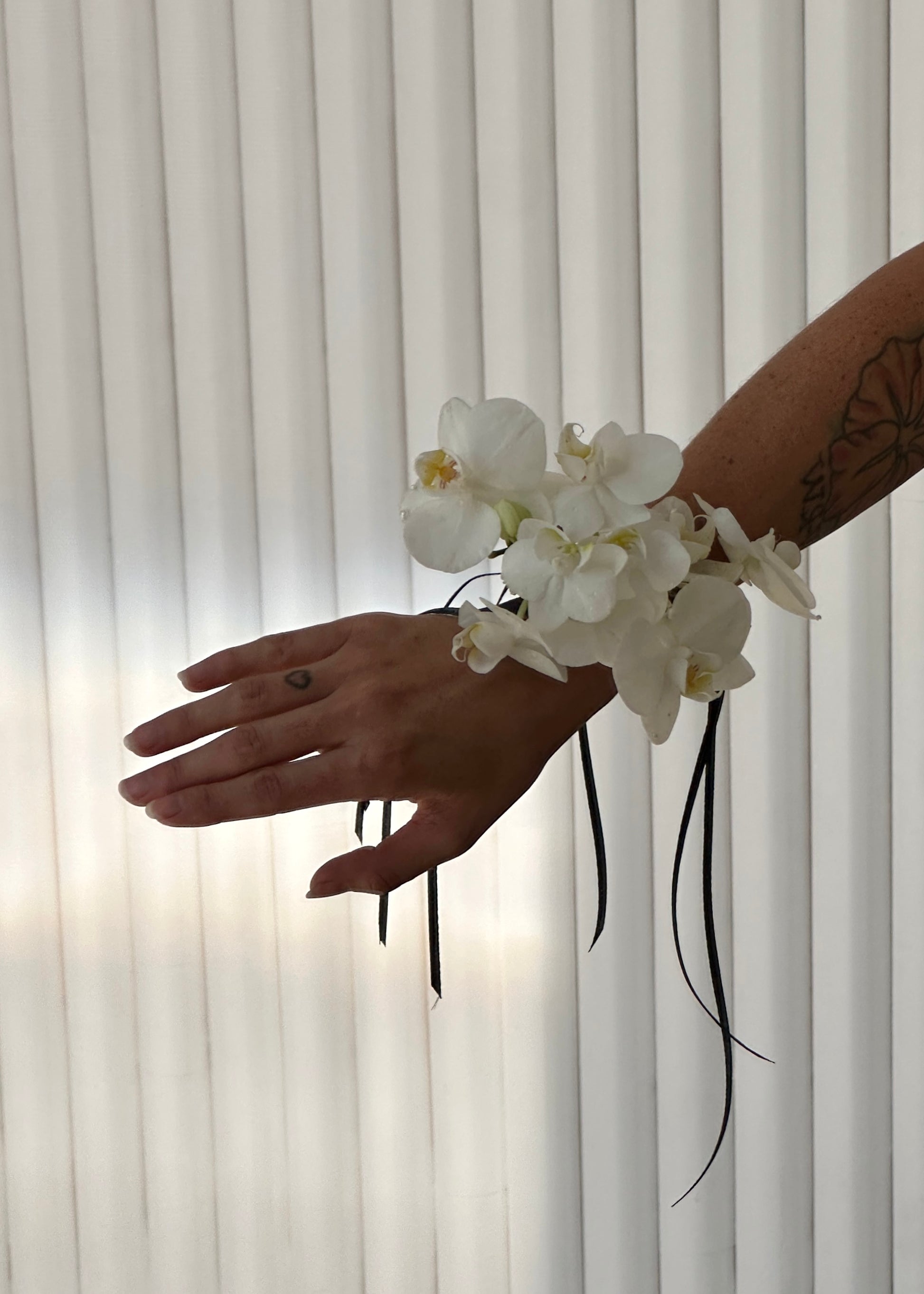 White orchid corsage worn on a wrist.
