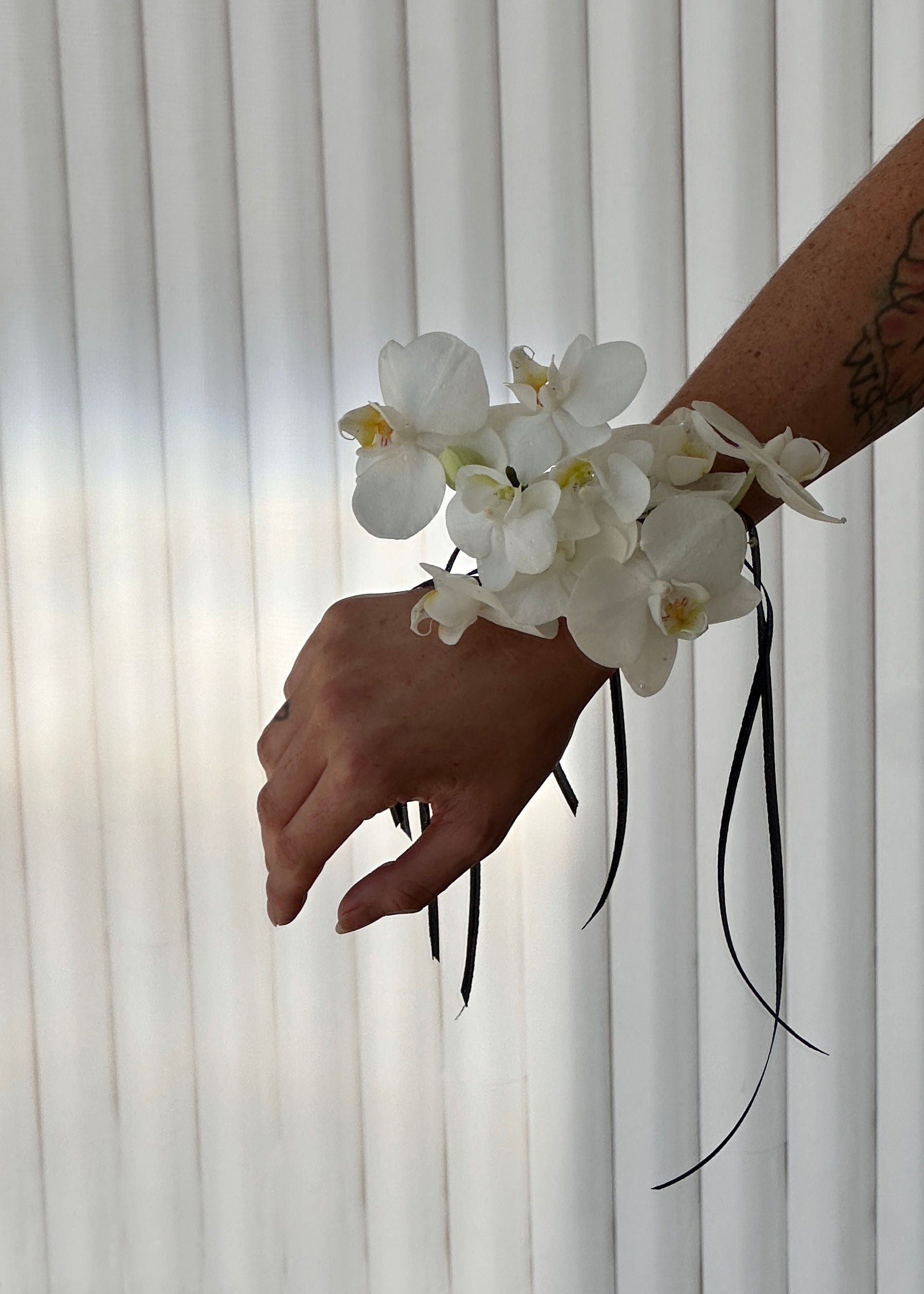 White orchid corsage worn on a wrist.
