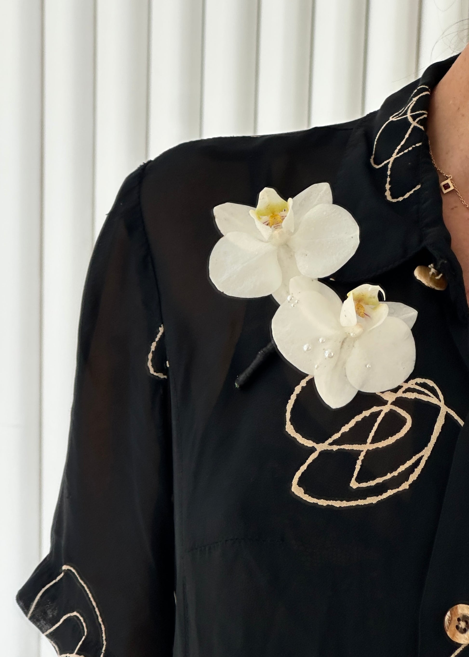 White orchid boutonniere pinned on a black shirt.